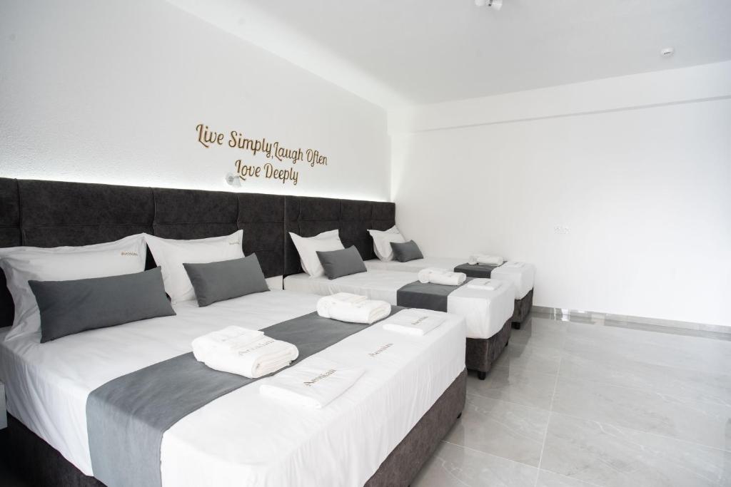 three beds in a room with a sign on the wall at Aeonian Luxury Suites Asprovalta, Adults Only & Kids 12 Plus in Asprovalta