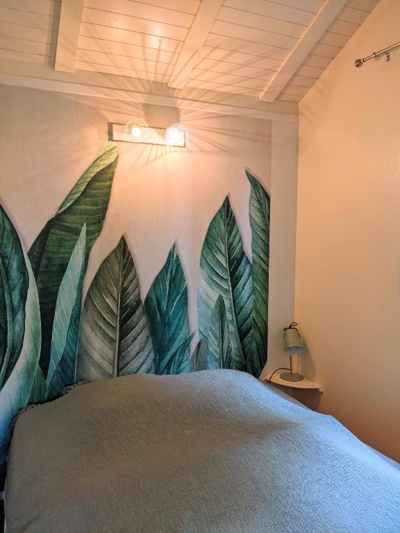 a bedroom with a mural of leaves on the wall at Camping Du Port De Plaisance in Péronne