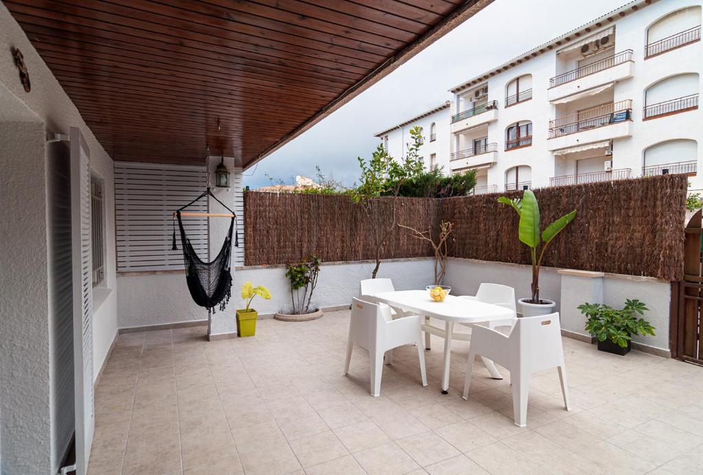 a patio with a white table and white chairs at Near beaches large private patio, aircon & community pool in Comarruga