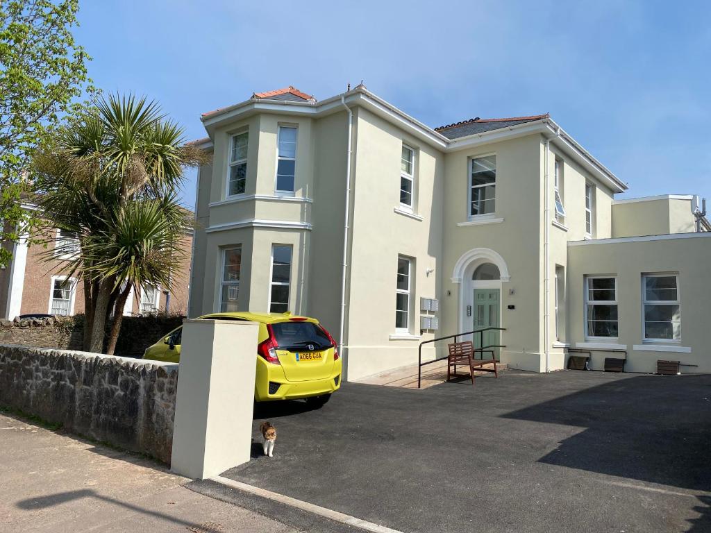 un coche amarillo estacionado frente a una casa en The Falstone Apartment, en Torquay