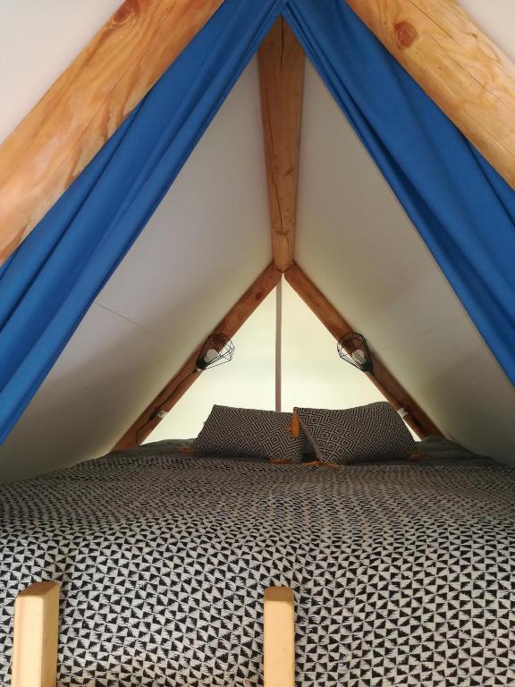 a bed in a blue and white tent at Camping Du Port De Plaisance in Péronne