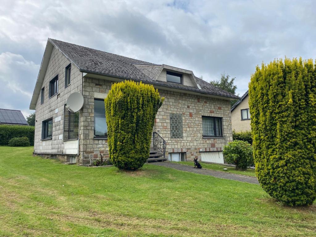 uma casa com duas árvores grandes em frente em La Villa 1968 em Bütgenbach