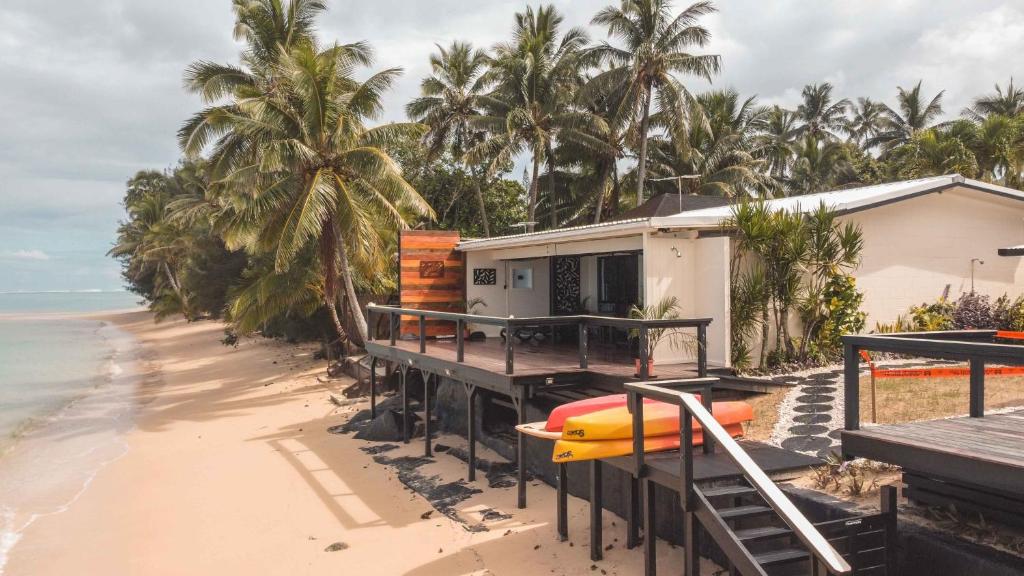 ein Haus am Strand mit einem Surfbrett auf einem Dock in der Unterkunft Take-A-Break Islander on the Beach Villa - Vaimaanga in Rarotonga