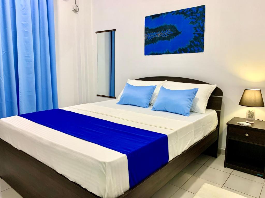 une chambre avec un grand lit avec des oreillers bleus dans l'établissement Mendila Cityscape Hikkaduwa, à Hikkaduwa