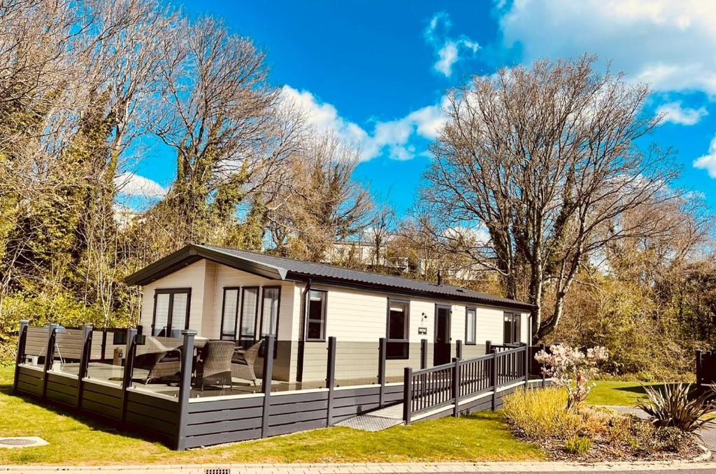 a small white cabin with a black fence at Luxury Lodge - Hoburne Devon Bay in Paignton