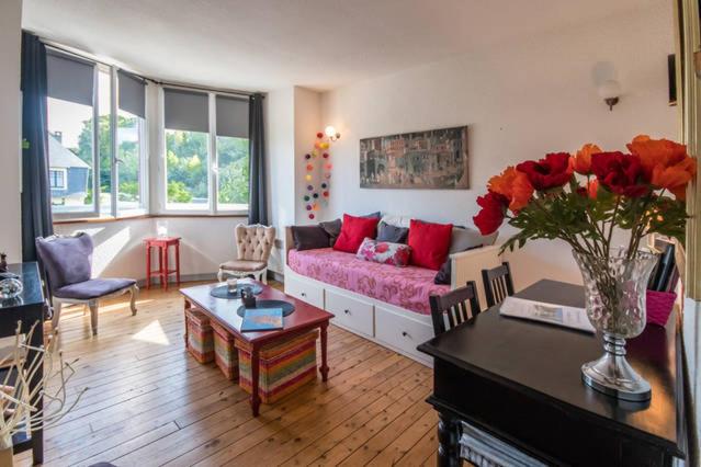 a living room with a couch and a vase of roses at Sables d'or Bel Appartement 300 m de la plage in Frehel