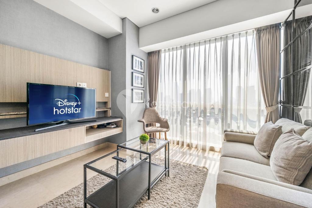 a living room with a couch and a tv at Quarter by Kozystay - Setiabudi in Jakarta