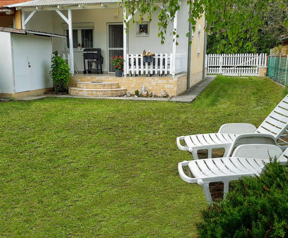 grupa białych ławek siedzących na podwórku w obiekcie Holiday Home Balatonszárszó w mieście Balatonszárszó