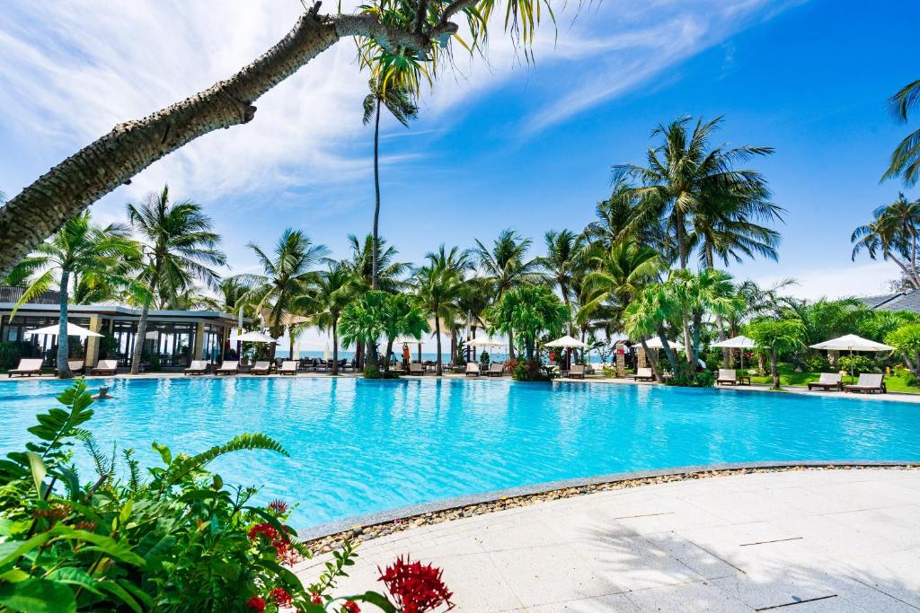 uma piscina no resort com palmeiras em Hoang Ngoc Beach Resort em Mui Ne