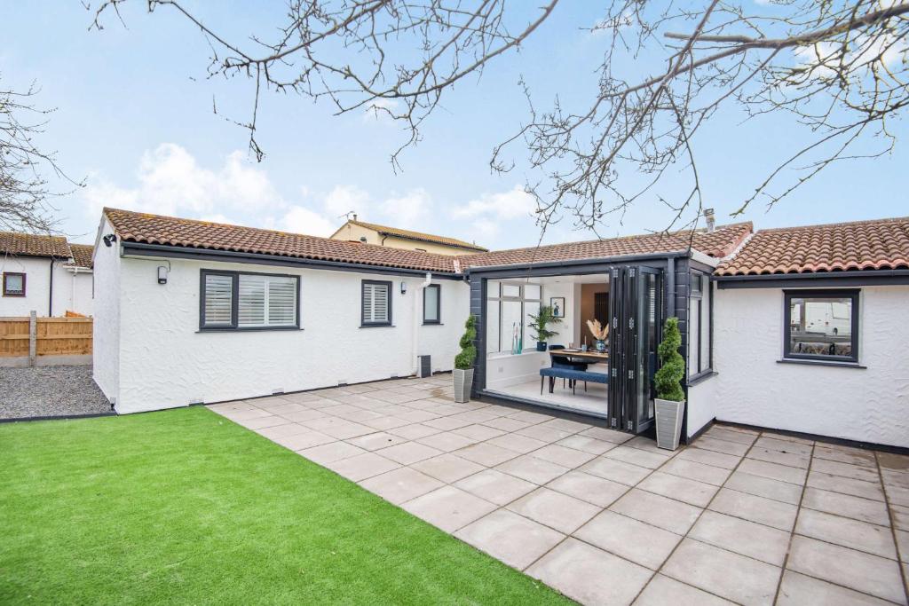 a white house with a patio and grass at Stunning Cottage with hot tub North Wales Coast in Abergele