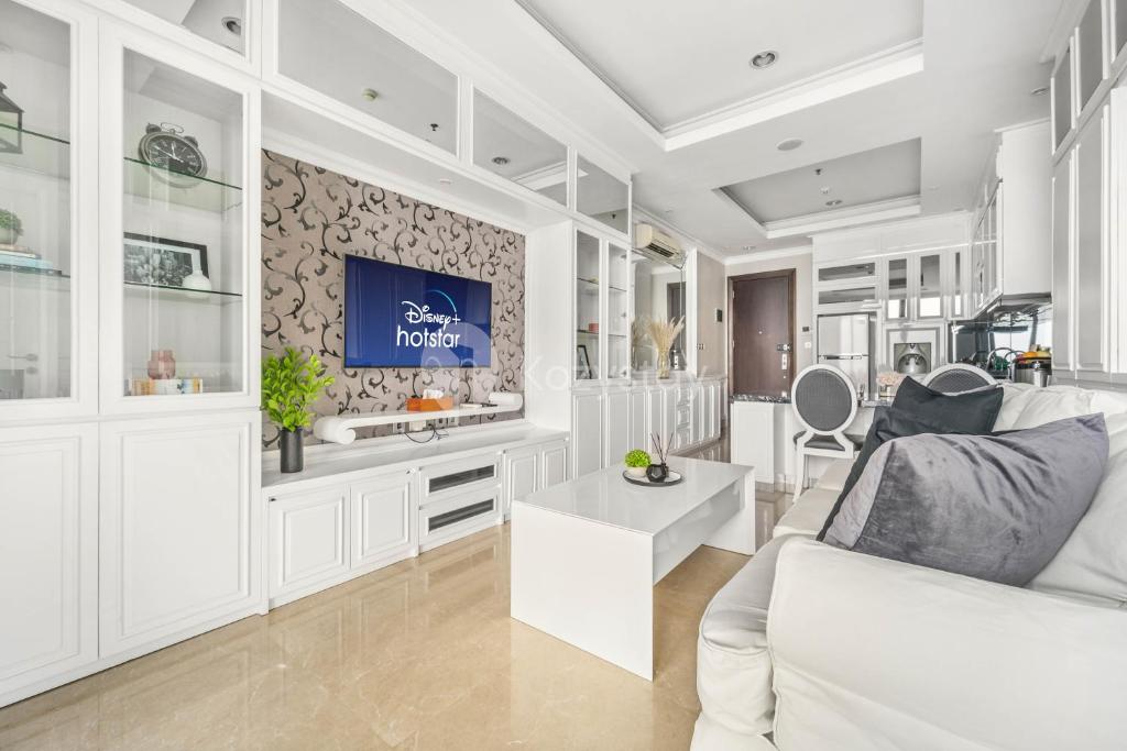 un soggiorno con divano bianco e TV di BLANC by Kozystay - 1BR Apartment in SCBD a Giacarta