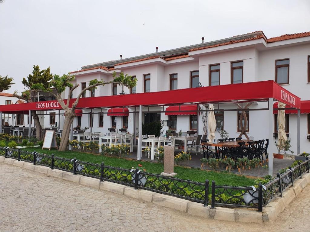 a hotel with tables and chairs in front of it at Teos Lodge in Siğacık