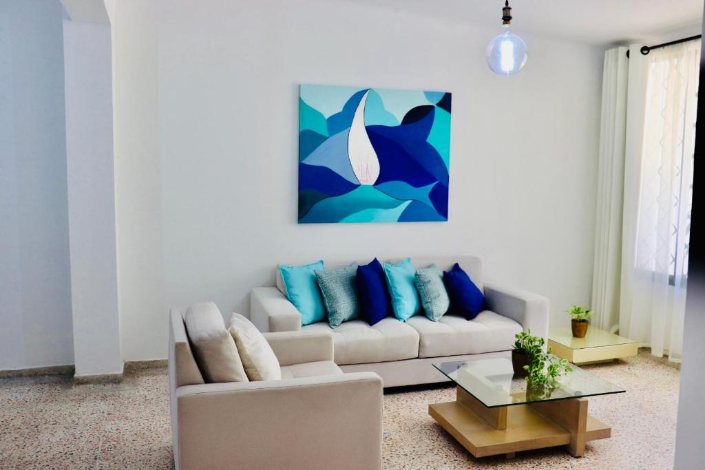sala de estar con sofá blanco y almohadas azules en Alojamiento espectacular, cerca al Malecón del Río, Puerta de Oro y CC Buenavista - Duchas con agua caliente, en Barranquilla