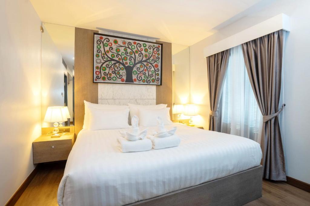 a bedroom with a large white bed with two towels at Marigold Lanna in Chiang Mai