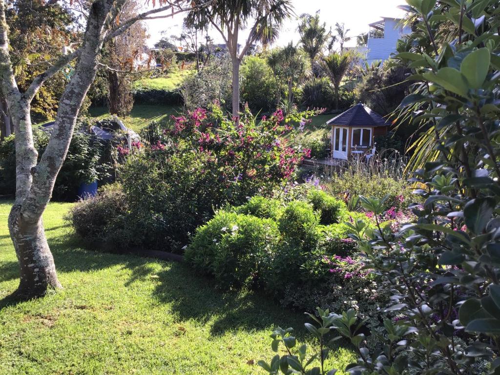 een tuin met een klein tuinhuisje en bloemen bij La Casita Waiheke in Oneroa