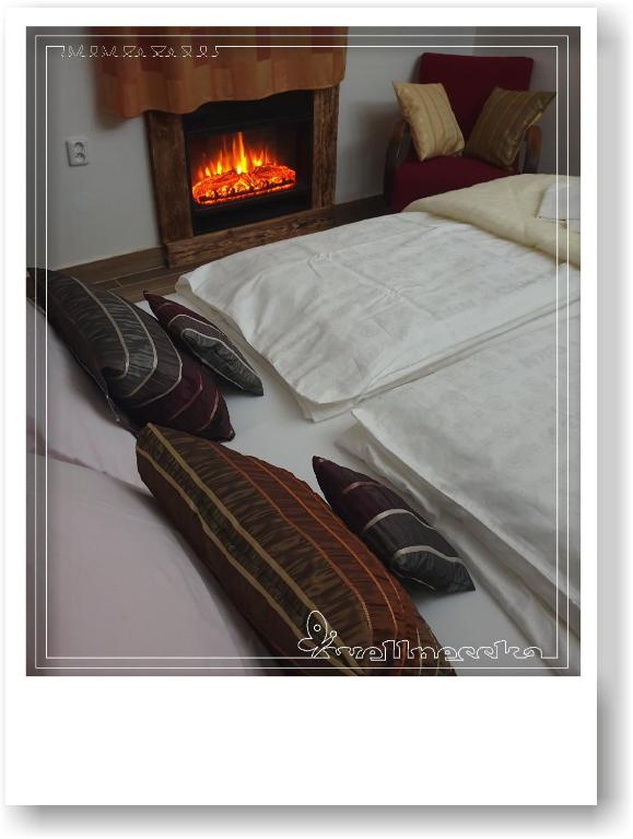 a bedroom with two beds with pillows and a fireplace at Wellnesska Vyhne in Vyhne