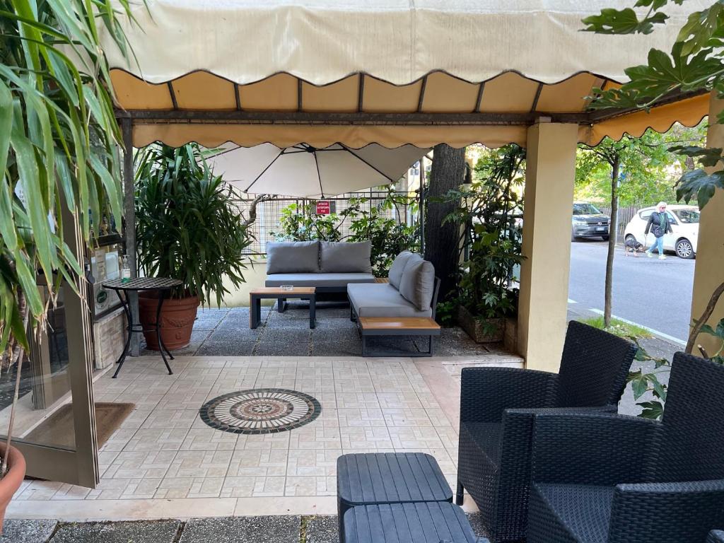 eine Terrasse mit einem Sofa und Stühlen unter einem Sonnenschirm in der Unterkunft Hotel Athena in Pesaro