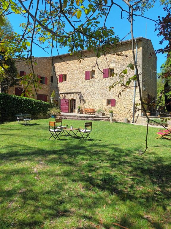 a building with two benches in a grass field at Le Vieux Moulin in Jouques