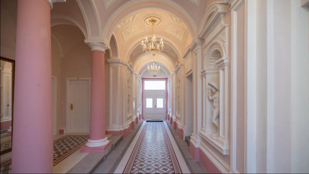 a hallway with pink columns and a door in a building at Angelo Roma in Prague