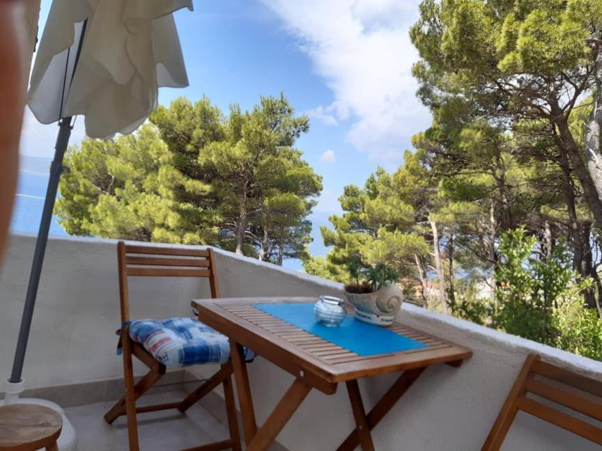 a wooden table and chair on a balcony with trees at Peace and quiet apartment in Brela, Croatia in Brela