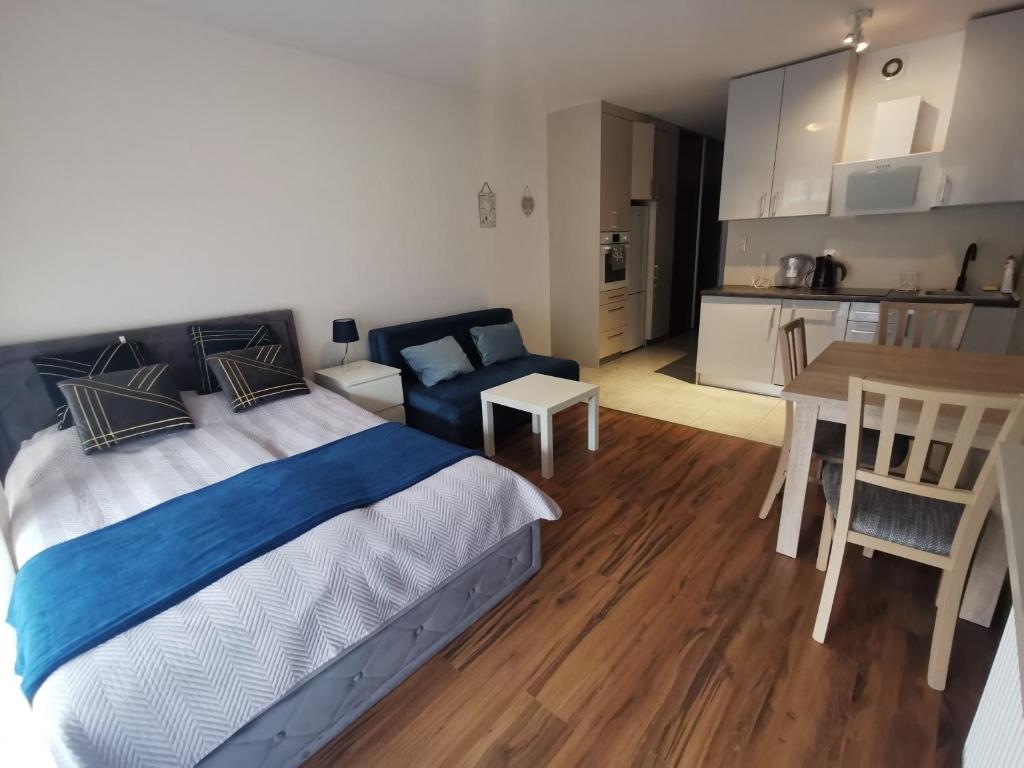 Cet appartement comprend une chambre avec un lit et une table ainsi qu'une cuisine. dans l'établissement Sea&Forest Pogorzelica Apartament Perłowy, à Pogorzelica