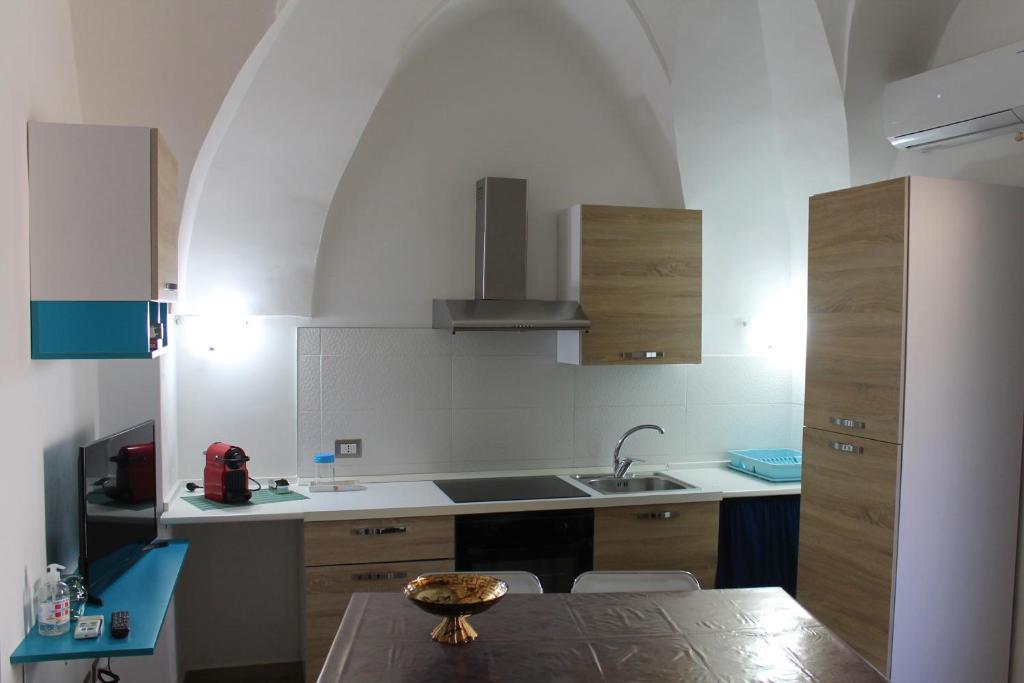 eine Küche mit einem Tisch, einem Waschbecken und einem Torbogen in der Unterkunft Casa Vacanze Natali-Stella in Porto Cesareo