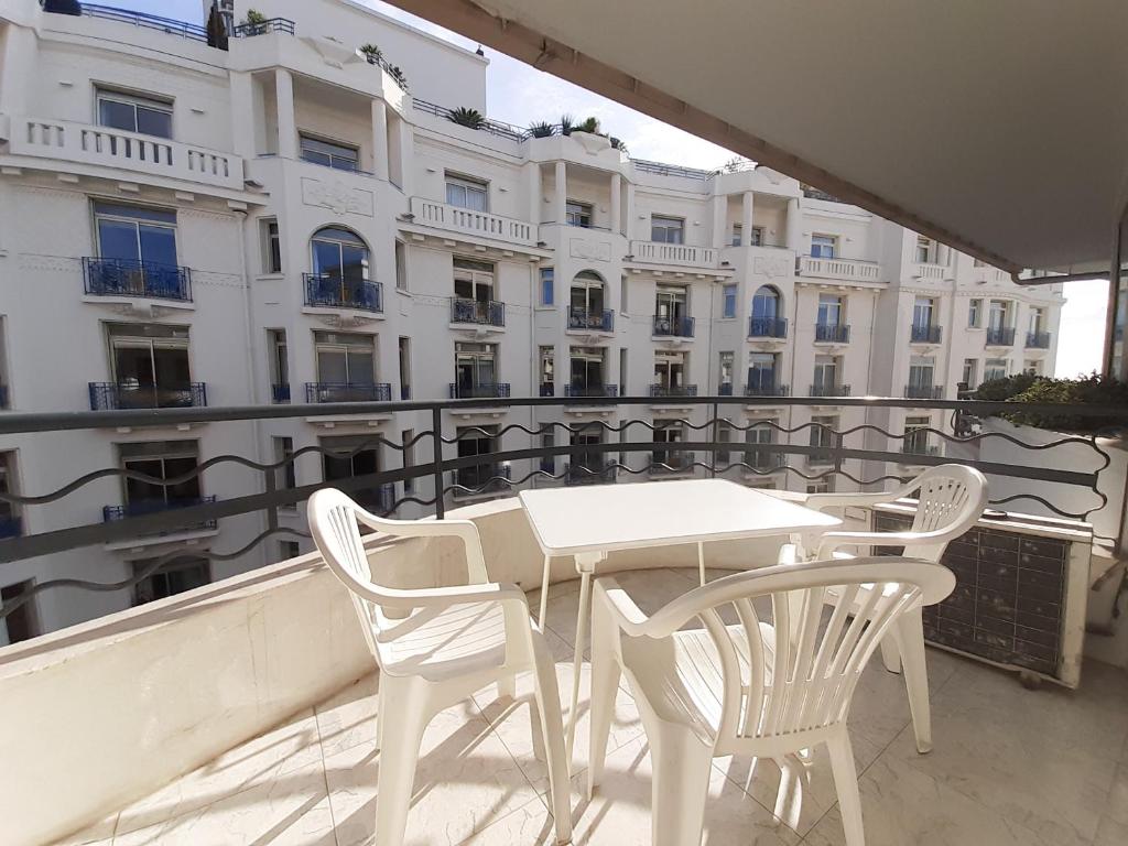 una mesa blanca y sillas en un balcón con un edificio en Palais des Iles, en Cannes