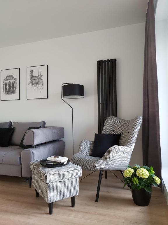 a living room with a couch and a chair and a table at Apartament 150 Zaspa VVita z ogrodem i tarasem in Gdańsk