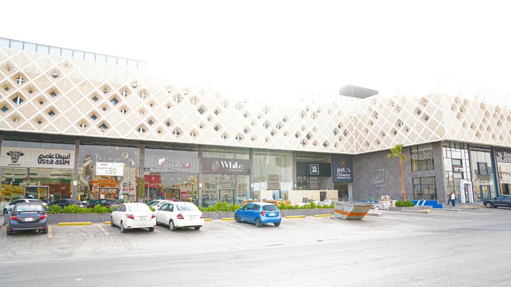 Clowzer Hotel Appartments في الرياض: موقف للسيارات مع وقوف السيارات أمام المبنى