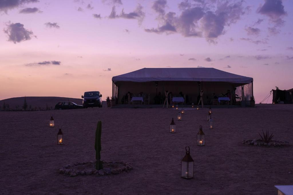 a tent in the desert with lights in the sand at Emeraude Camp Agafay in El Karia