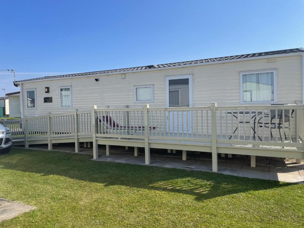 a mobile home with a deck and a house at The Pearl - Deluxe Access Caravan in Skegness