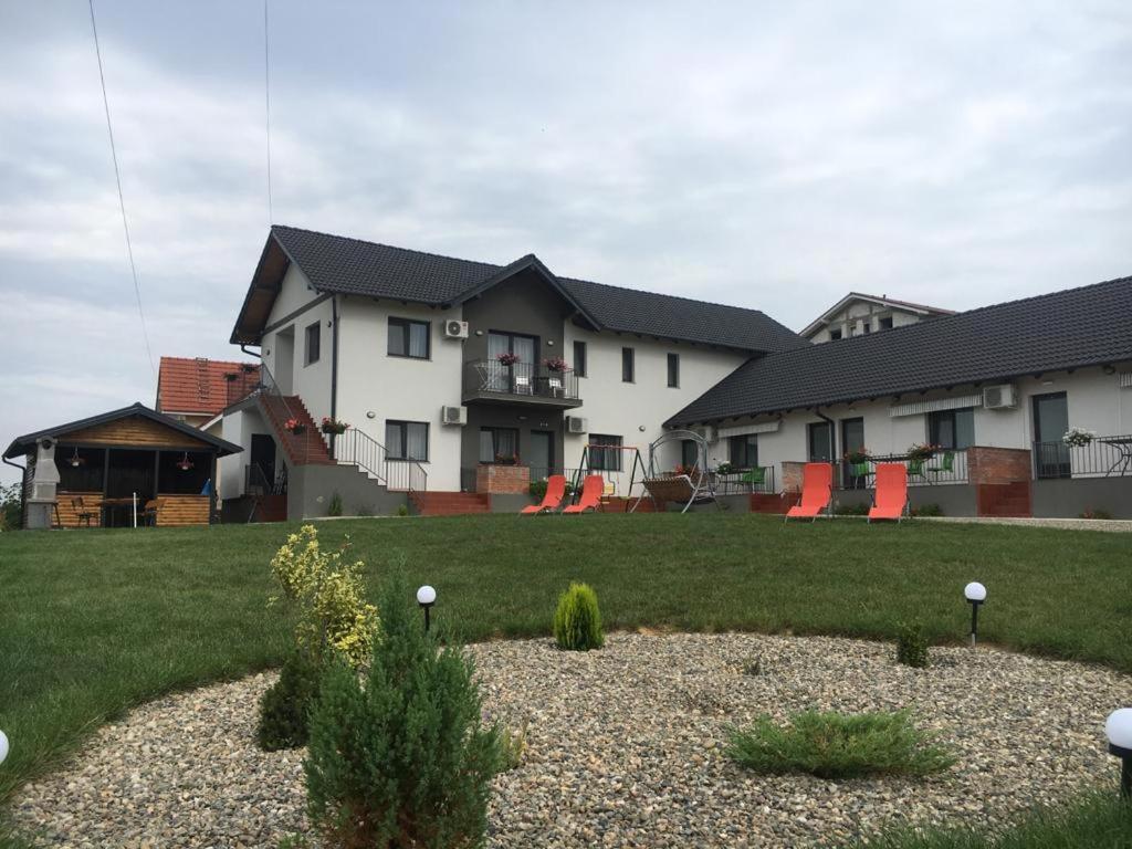 a house with red chairs in a yard at Pensiunea Gloria in Baile Felix