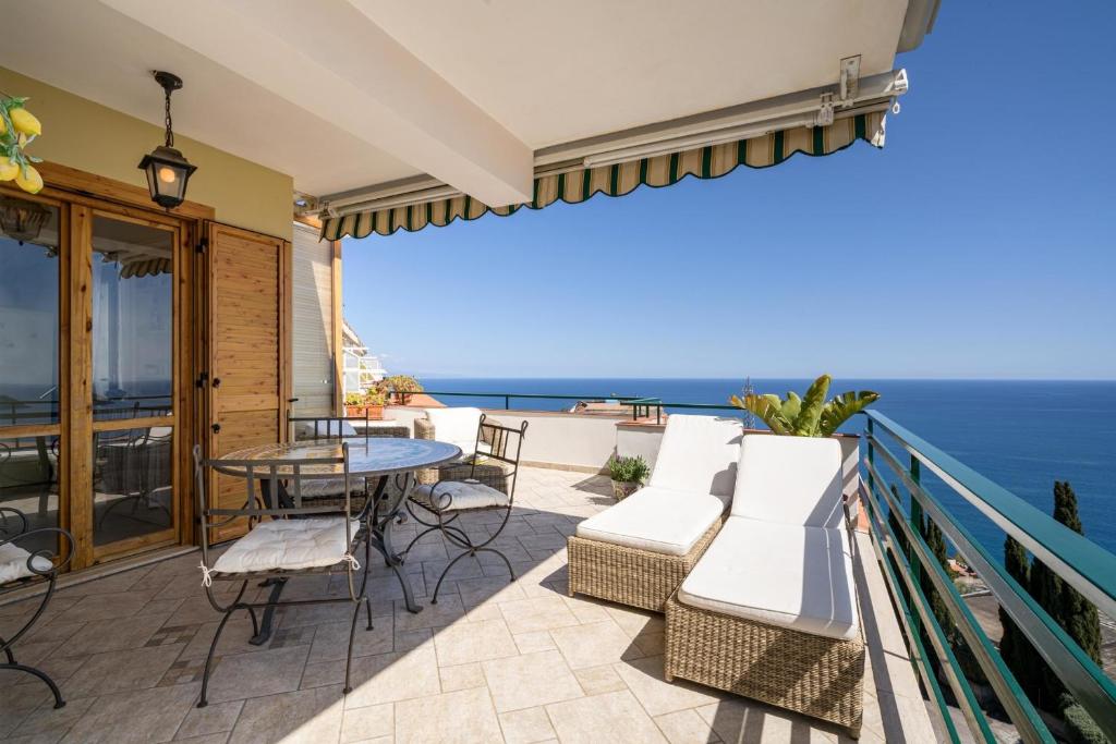 eine Terrasse mit einem Tisch, Stühlen und Meerblick in der Unterkunft Ferienhaus Sicilysun Holidays Emilia in Letojanni