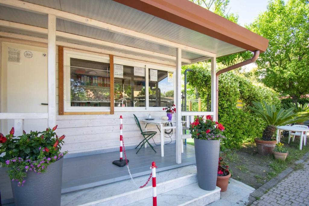 un porche de una casa con una mesa y flores en Camping Linus, en Marina di Massa