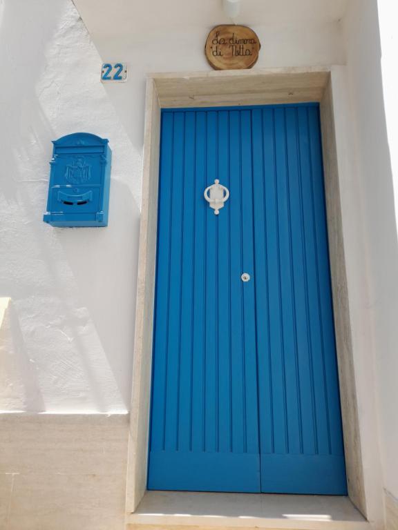 una porta blu in un muro bianco con una cassetta della posta blu di La Dimora di Netta a Carovigno