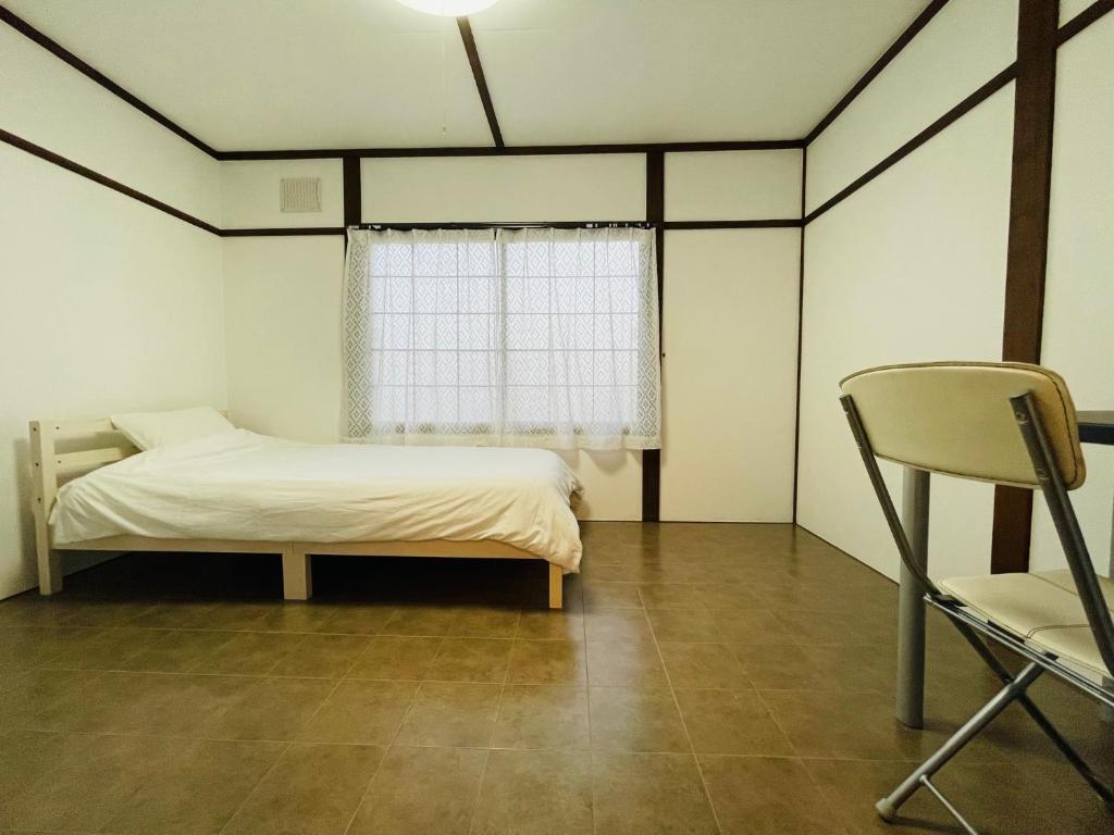 a bedroom with a bed and a chair and a window at サービスアパ―トメントSAPPORO札幌さくら2-3 in Sapporo
