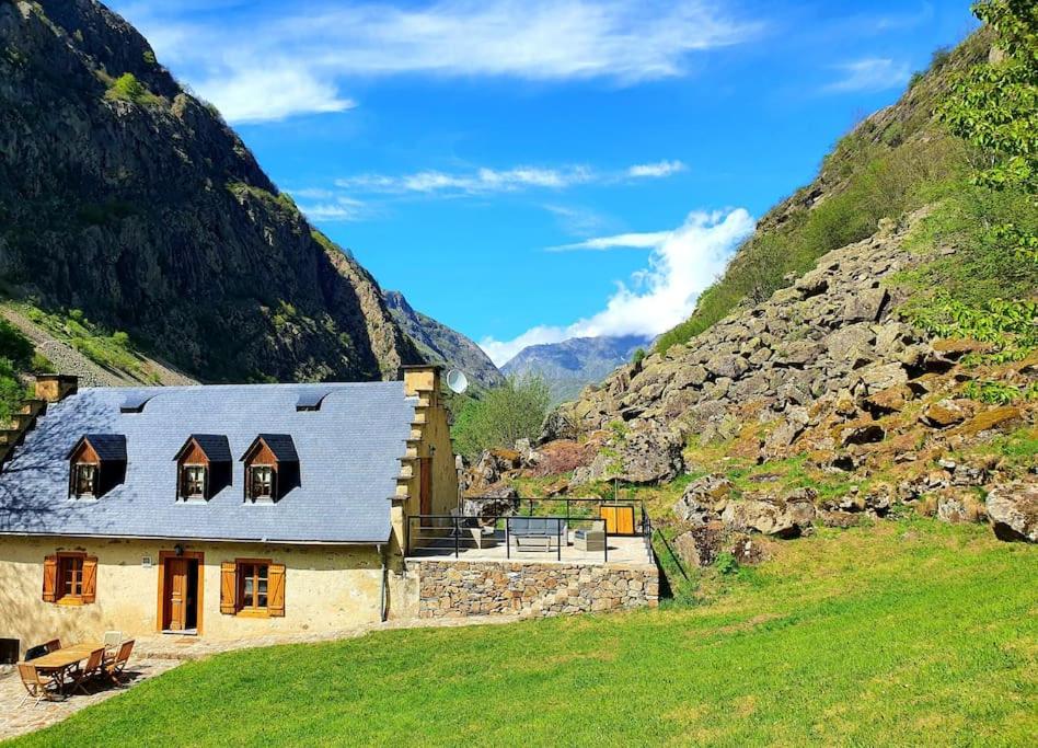 a house in a mountain with a grassy field at Maison authentique in Gavarnie