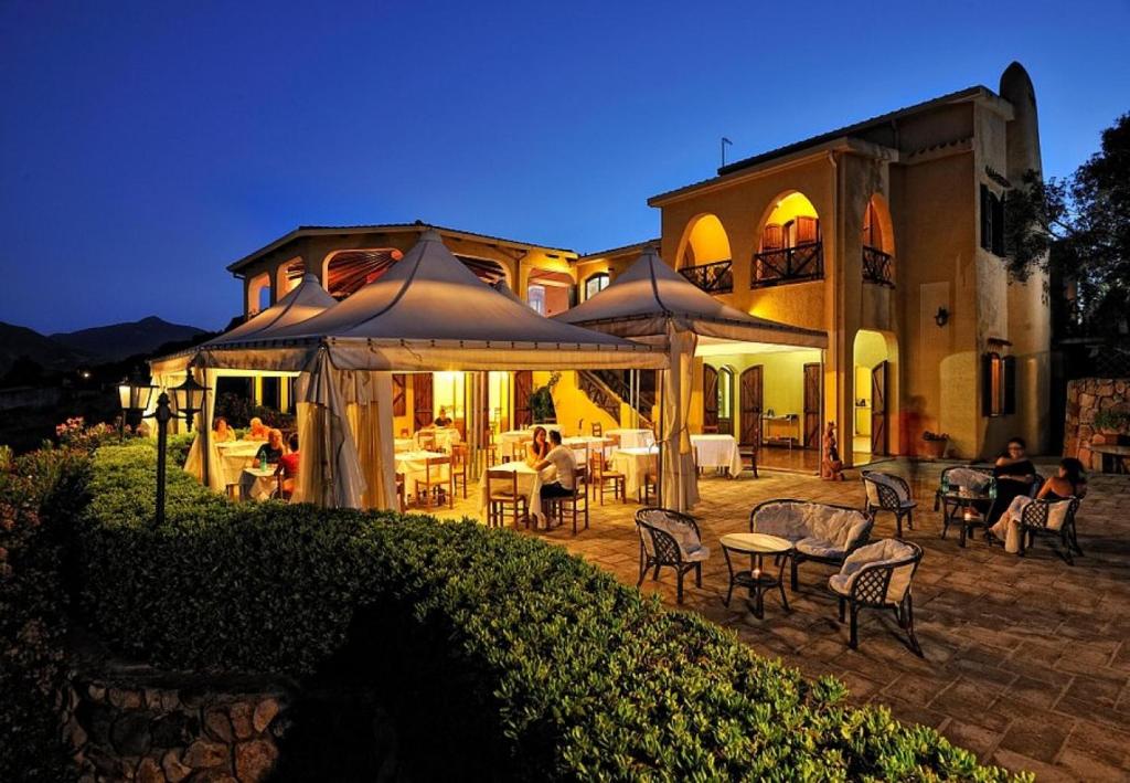 a large house with a patio with tables and chairs at Hotel Genna 'e Masoni in Cardedu