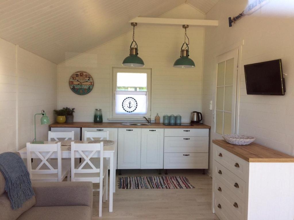 a kitchen with white cabinets and a table and chairs at BIAŁE DOMKI in Rusinowo