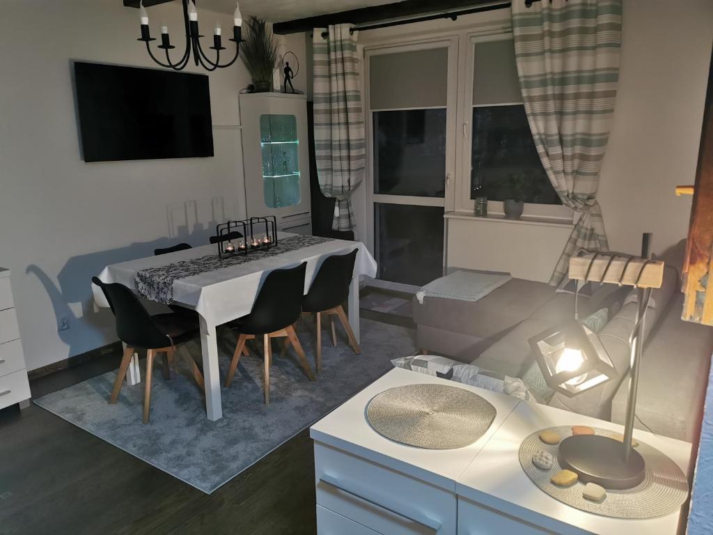 Apartament Woda Morska في أوستكا: غرفة معيشة مع طاولة وكراسي بيضاء