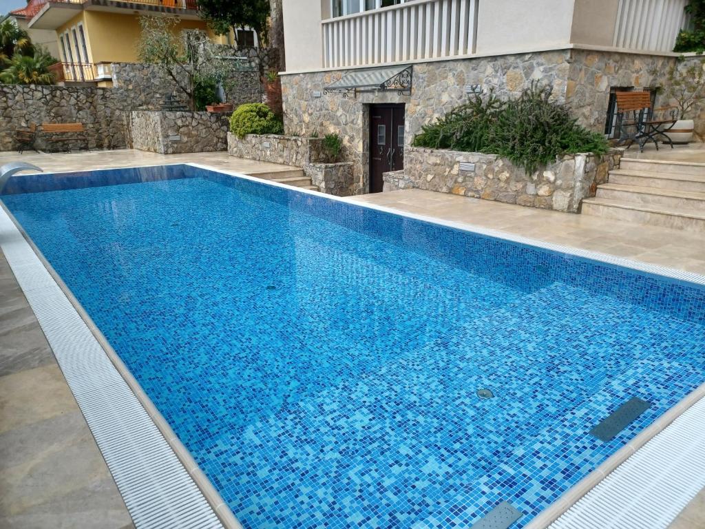 a swimming pool with blue water in front of a house at Hotel Abalone in Crikvenica