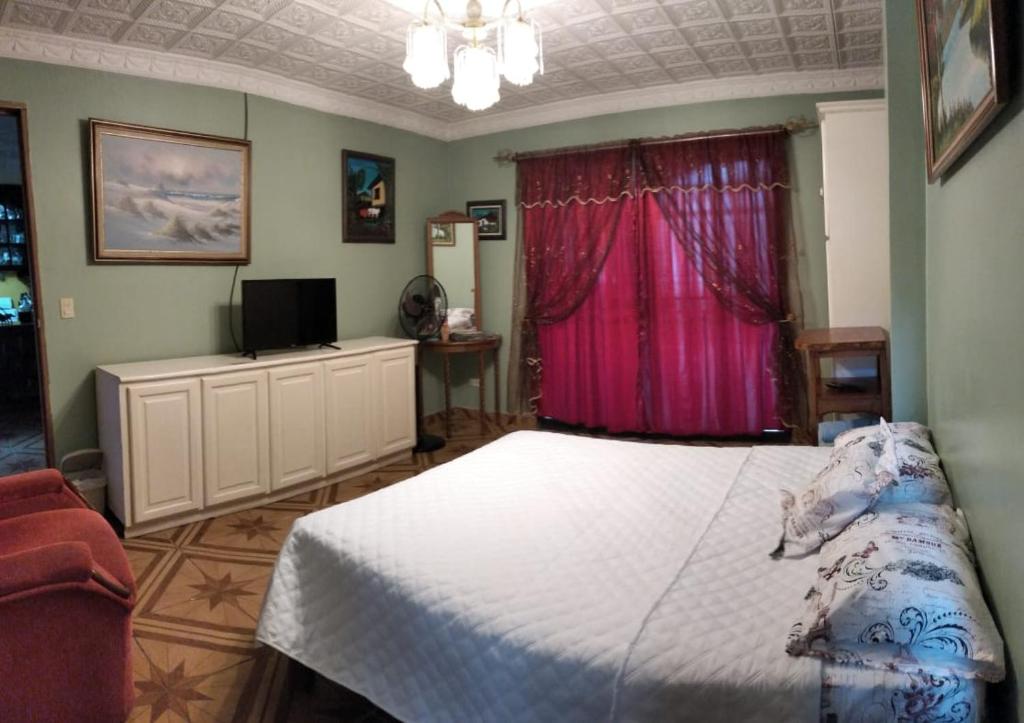 1 dormitorio con cama blanca y ventana rosa en Alexander b&b en Alajuela