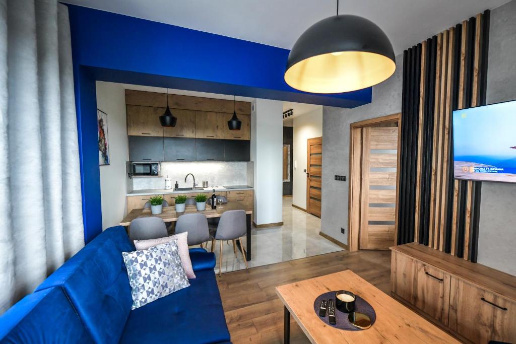 Il comprend un salon avec un canapé bleu et une cuisine. dans l'établissement Apartament Komfort 17, à Zator