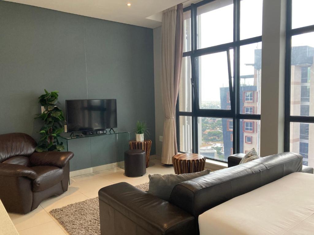 a living room with a couch and a television at Urban Awe Apartment- iTowers 18th Floor in Gaborone
