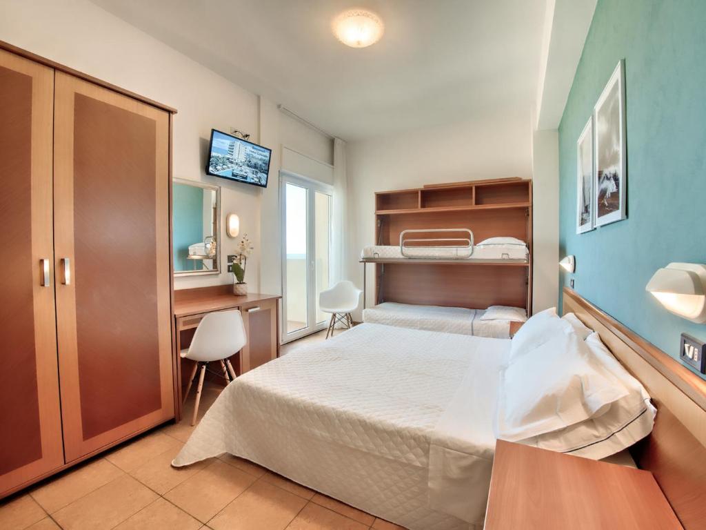 ein Hotelzimmer mit einem Bett, einem Schreibtisch und einem Bett in der Unterkunft Hotel Colorado Cesenatico in Cesenatico