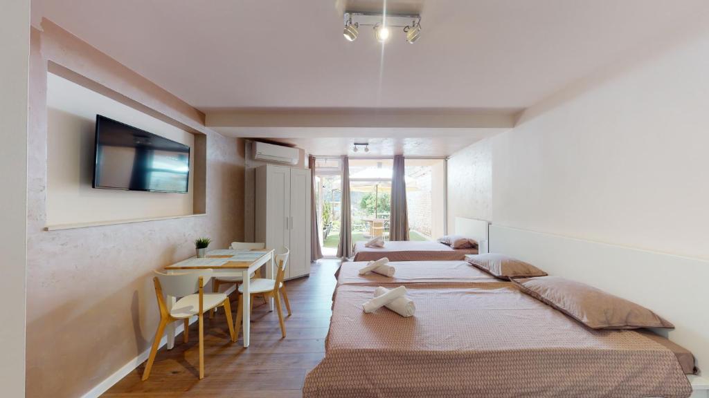 Habitación con 3 camas, mesa y TV. en Markoni 5, en Burgas