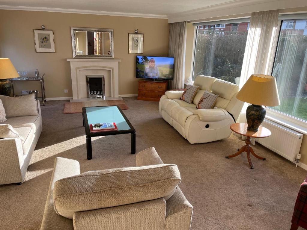 uma sala de estar com sofás e uma televisão em 'Sounion' - Fabulous, spacious modern house with large private garden in Leafy Lytham em Lytham St Annes