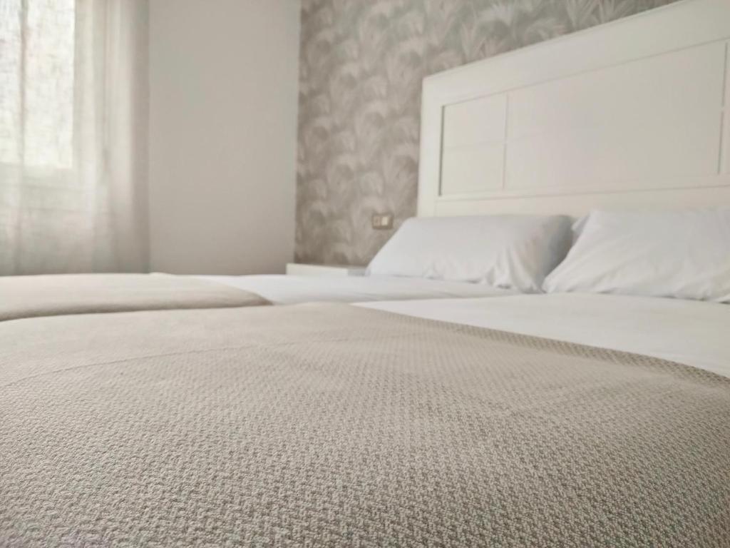 a bedroom with two white beds and a window at Second Home Arzúa apartamentos in Arzúa