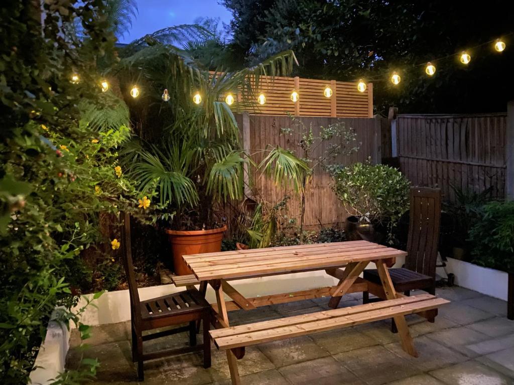een houten picknicktafel en bank in een tuin 's nachts bij Spacious 2-bed flat with garden, 3 minutes walk from Oval tube station in Londen