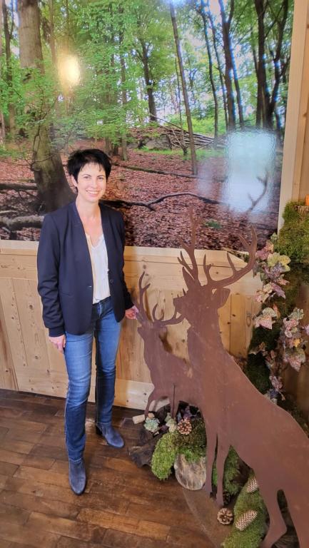 een vrouw die naast een standbeeld van een boom staat bij Pension Zum alten Rathaus in Schleiden